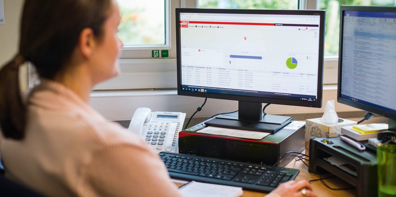 Hilti darbiniece sēž pie galda, strādājot ar datoru.
